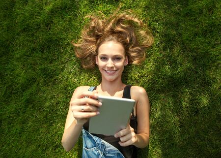 girl sitting in the park on the background of grass, happyの写真素材