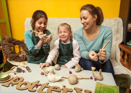 Mother and daughters mold with clay, pottery children