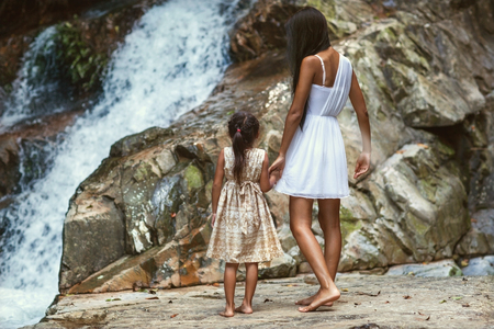 Mother and daughter walking near a waterfall in the mountains in the jungleの写真素材
