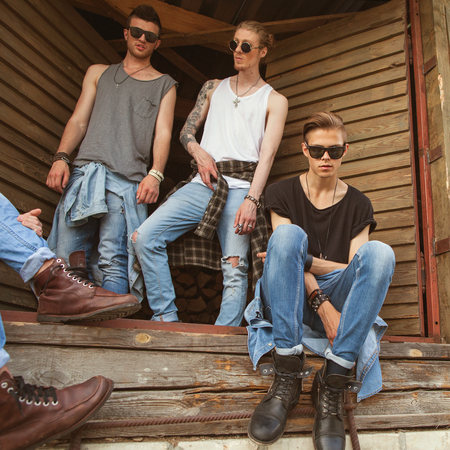 fashion hipster guys sitting near the wall, dressed in jeans and a plaid shirt, sunglasses, Vogue Styleの写真素材