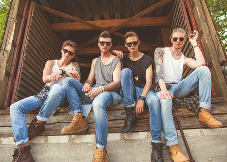 fashion hipster guys sitting near the wall, dressed in jeans and a plaid shirt, sunglasses, Vogue Styleの写真素材