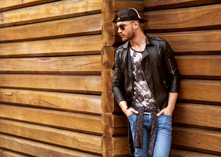 Portrait of young beautiful fashionable man against wooden wall. Hipster style guyの写真素材