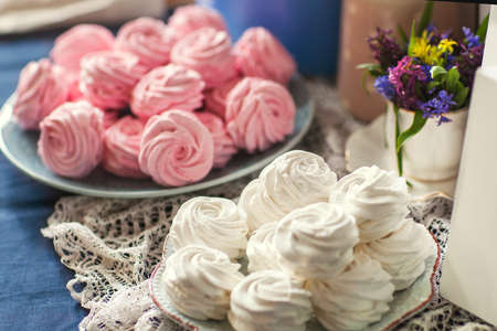 Pink delicious marshmallow lies on a blue plate on a blue background, closeupの写真素材