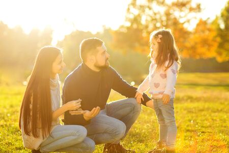 mother and dad with daughter at sunset playing