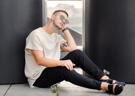 Hipster style guy. Fashion man standing near black wallの写真素材