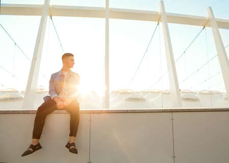 fashion guy sitting at sunset posing