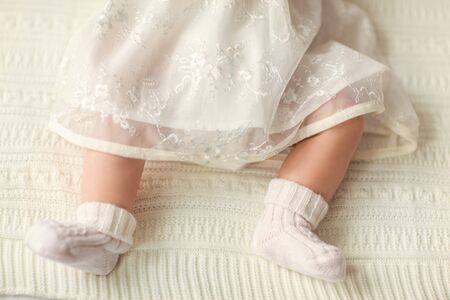 legs of a little girl with a white bow lies on the couch, on a white background.の写真素材