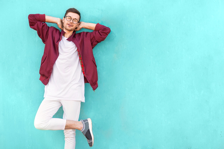 fashion guy in glasses poses near the wall the color of the sour waveの写真素材