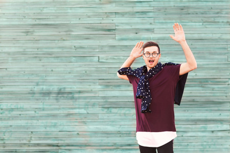 fashion guy in glasses poses near a wooden wall in blue