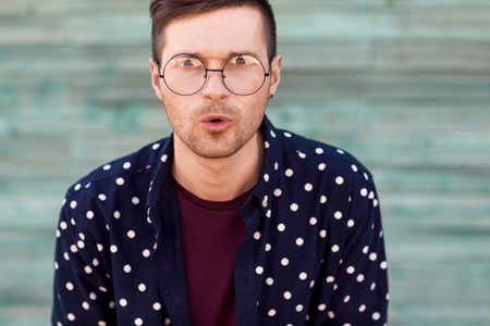 fashion guy hipster in fashion glasses posing on a wooden background