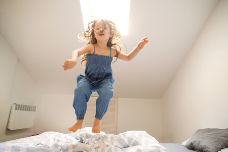 little girl playing and jumping at homeの写真素材