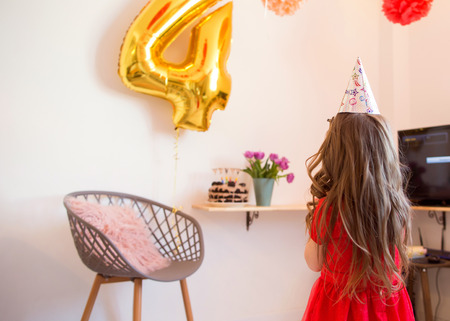 happy little girl celebrating the fourth birthday at homeの写真素材