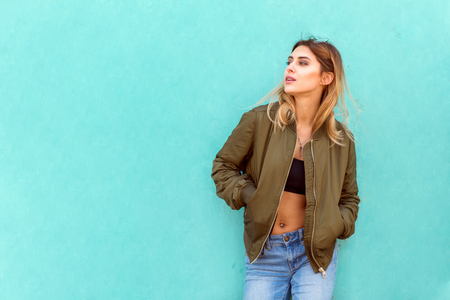 fashion girl in round glasses stands posing near a turquoise wallの写真素材