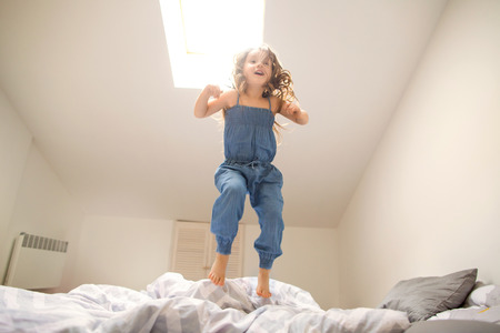 little girl playing and jumping at homeの写真素材