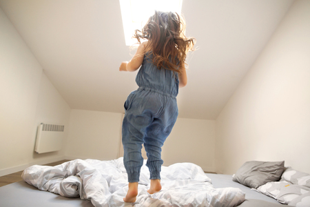 little girl playing and jumping at homeの写真素材