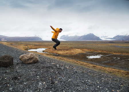 Tourist jumps over rocks in Icelandの写真素材