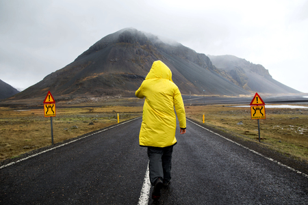 guy in a yellow cloak is walking down the road in the mountains, a tourist. The concept of freedom.の写真素材
