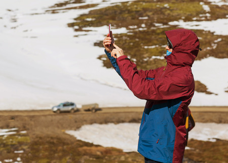 guy tourist taking pictures of a waterfall in the mountains of Iceland