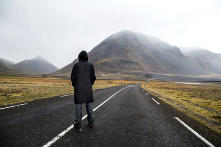 Guy in a yellow cloak is walking down the road in the mountains, a tourist. The concept of freedom.の写真素材