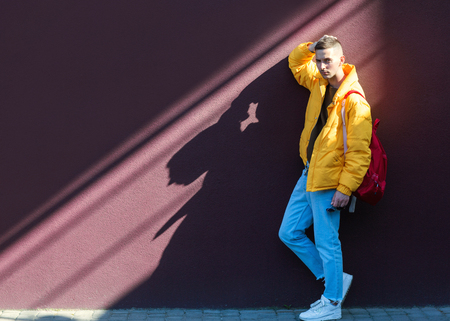 fashion guy standing near a viola wall in yellow clothesの写真素材