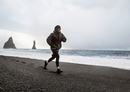 Guy athlete runs on a black beach in Iceland