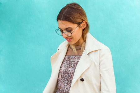 fashion girl in round glasses stands posing near a turquoise wallの写真素材