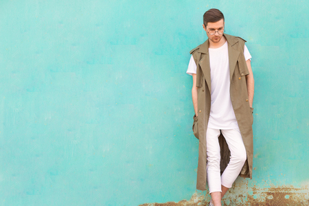 A fashionable man in a round table standing next to a turquoise wallの写真素材