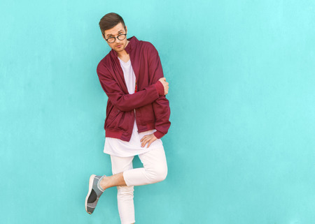 fashion hipster guy in glasses poses near the wall the color of the sour wave