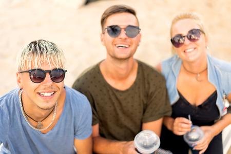 three friends on the beach drinking cocktails fun