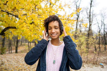 africanamerican girl listening to music in the autumn parkの写真素材