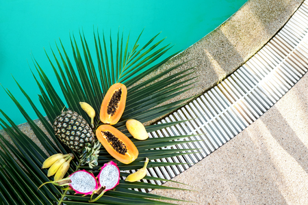 tropical fruits lie on palm leaves near the poolの写真素材