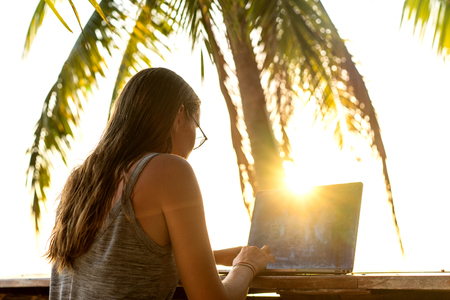 girl freelancer working on the sea at sunset with a computerの写真素材