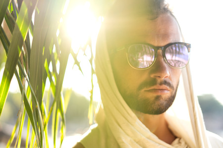 fashion handsome guy at sunset posing in a white robe near the rocks on sunglassesの写真素材