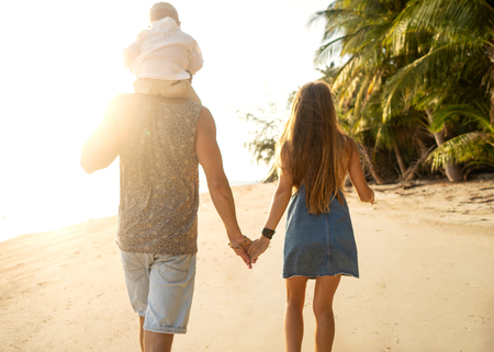 family walk along the beach at sunset with his son: back view silhouetteの写真素材