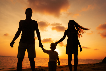 family walk along the beach at sunset with his son, silhouetteの写真素材