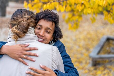 guy with an african  girl in love hugging  in autumn park walk at sunsetの写真素材