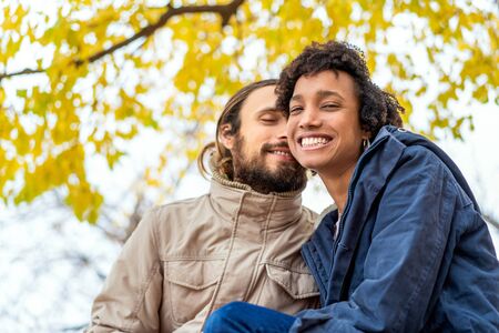 guy with an african girl in love in autumn park walk at sunsetの写真素材