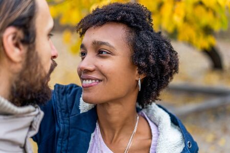 guy with an african  girl in love in autumn park walk at sunsetの写真素材