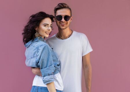 fashion couple in sunglasses posing on pink wallの写真素材