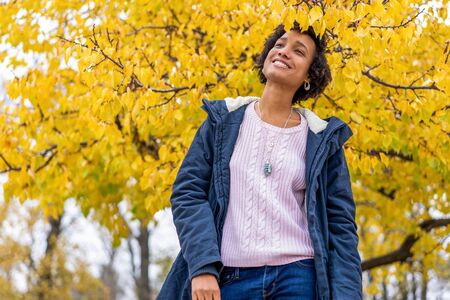beautiful african girl in autumn park outdoors smilingの写真素材