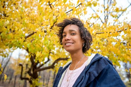 beautiful african girl in autumn park outdoors smilingの写真素材