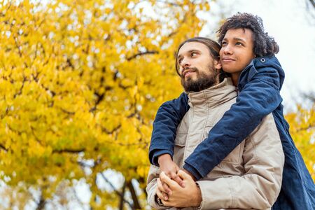 guy with an african  girl in love hugging  in autumn park walk at sunsetの写真素材