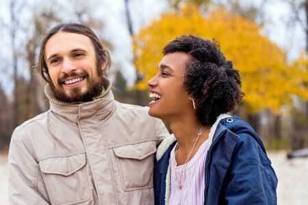 guy with an african american girl in love in autumn park walk at sunsetの写真素材