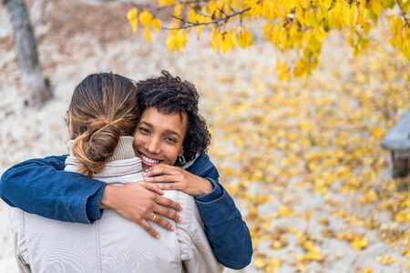 guy with an african  girl in love hugging  in autumn park walk at sunsetの写真素材