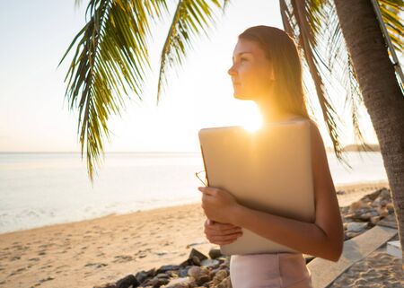 freelancer girl with a computer among tropical palm trees work on the islandの写真素材