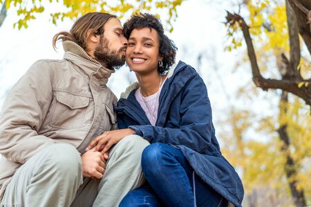 guy with an african girl in love in autumn park walk at sunsetの写真素材