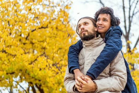 guy with an african  girl in love hugging  in autumn park walk at sunsetの写真素材