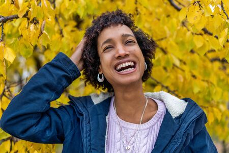 beautiful african girl in autumn park outdoors smilingの写真素材