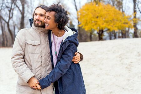guy with an african american girl in love in autumn park walk at sunsetの写真素材