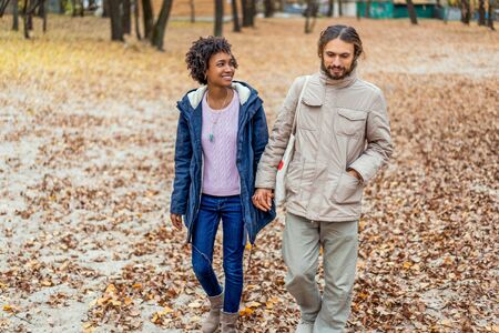 guy with an african girl in love in autumn park walk at sunsetの写真素材